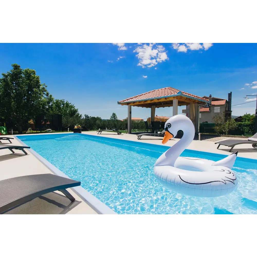 Vit uppblåsbar svanflotte med svart kontur och orange näbb i glasfiberpool Jamaika 25x3 75x1 50m